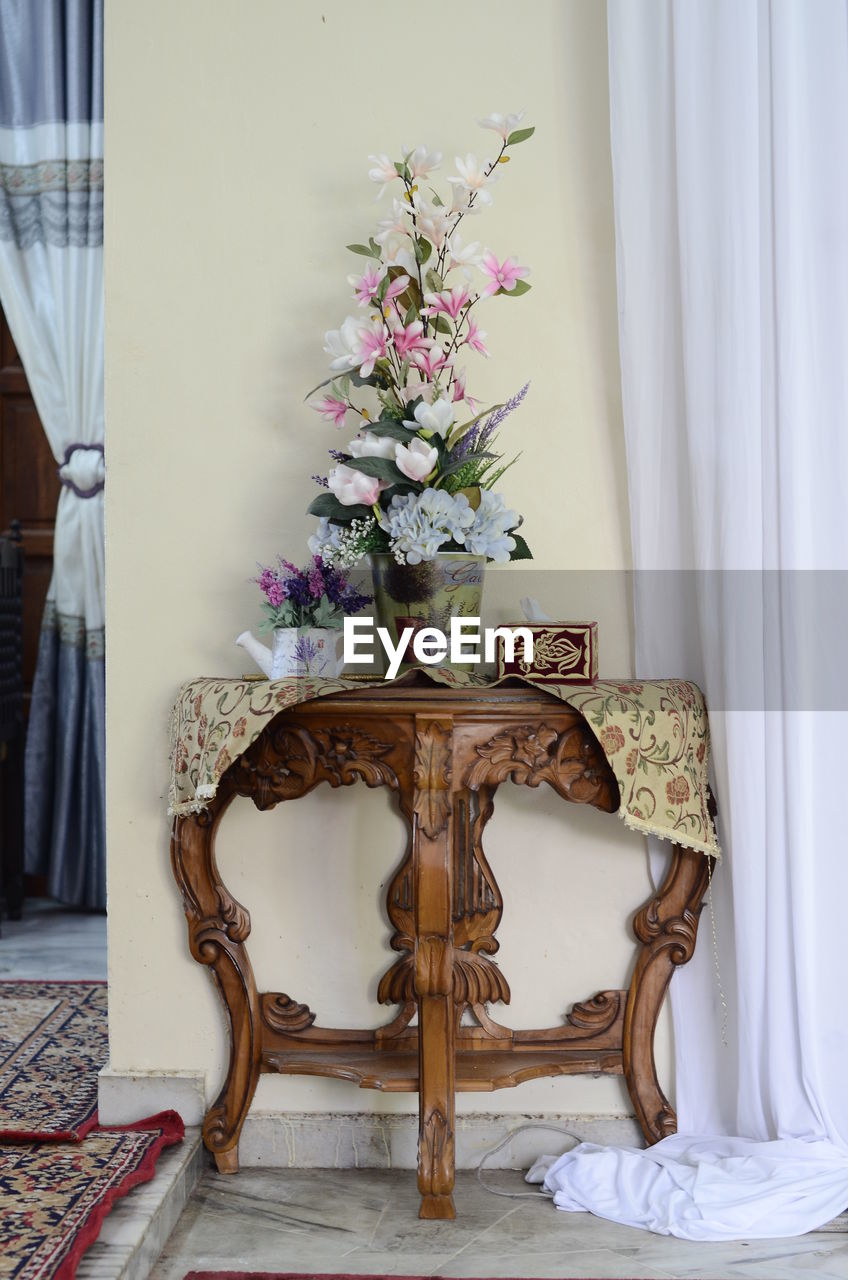 Flower vase on table against wall at home