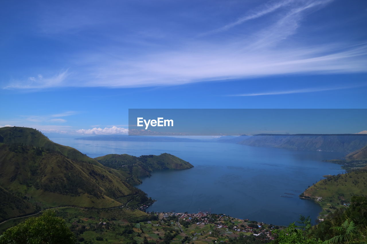 Scenic view of sea and mountains against blue sky