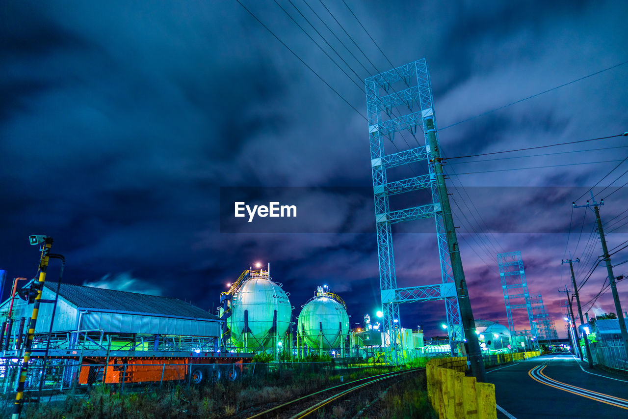 ILLUMINATED FACTORY AGAINST SKY AT DUSK