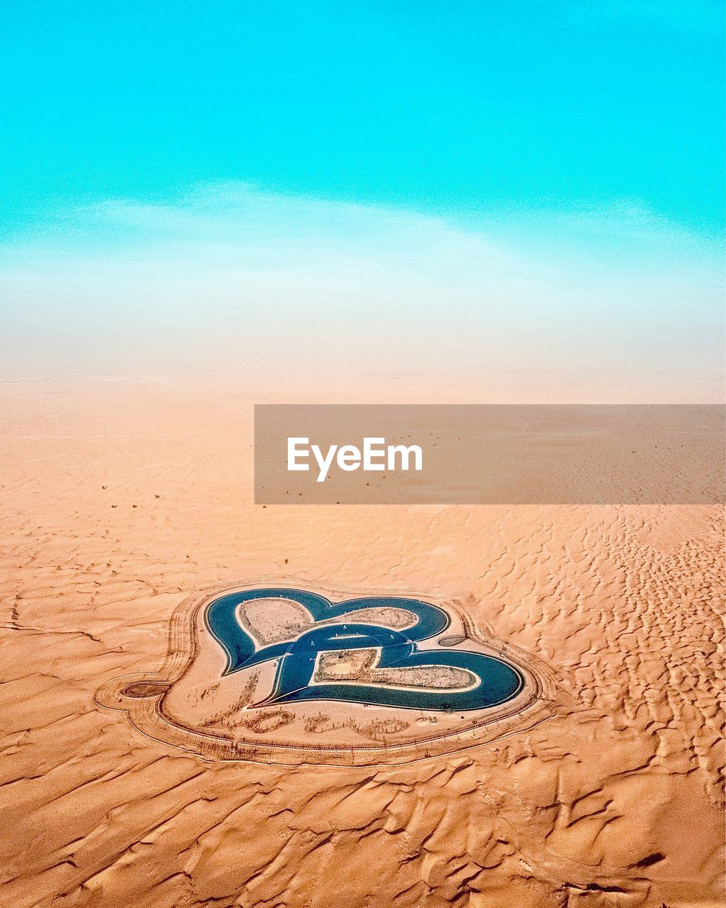 High angle view of heart shapes made on sand against blue sky