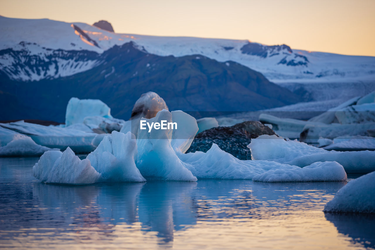 Scenic view of icebergs on lake against sky during sunset