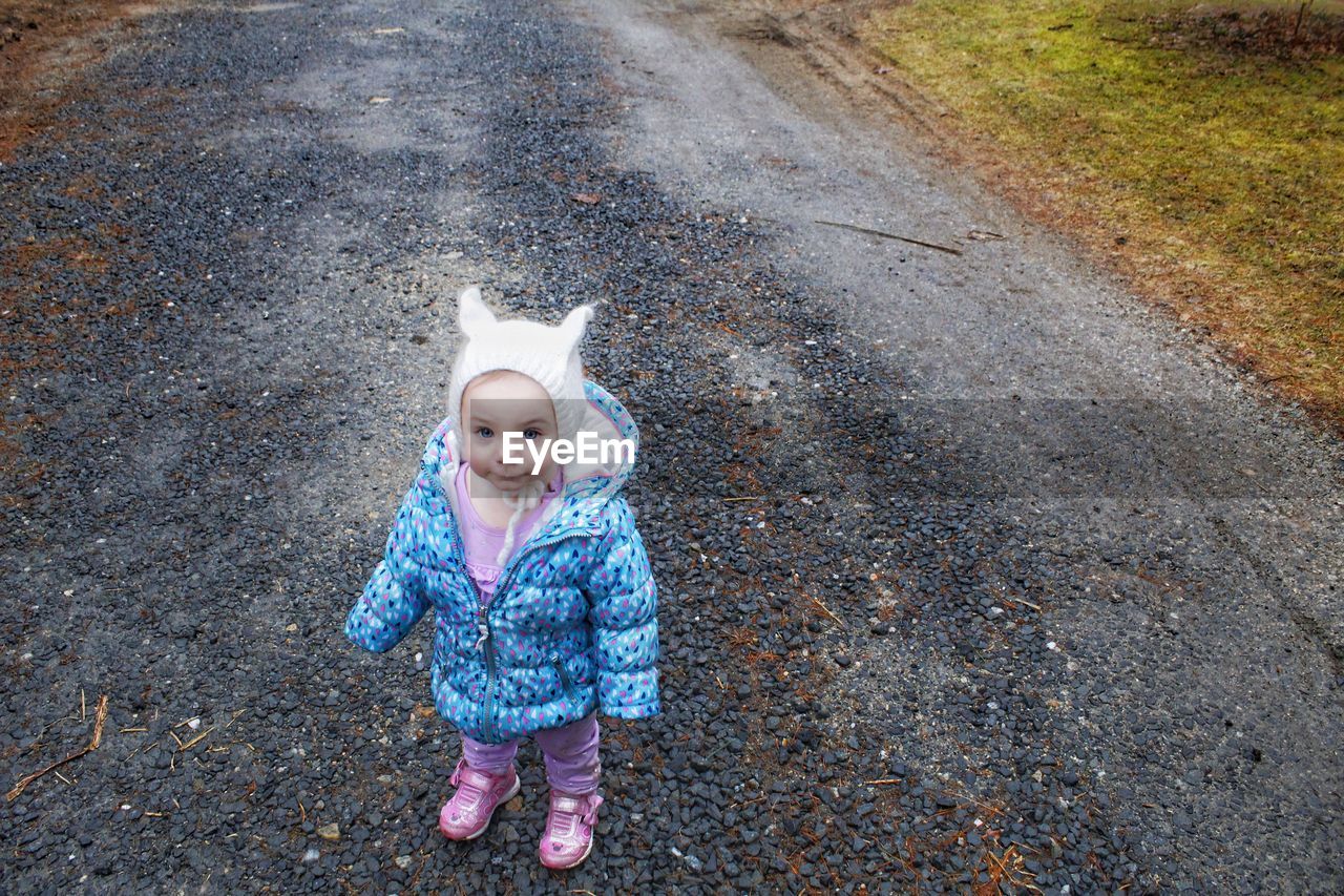 High angle portrait of cute baby girl standing on road