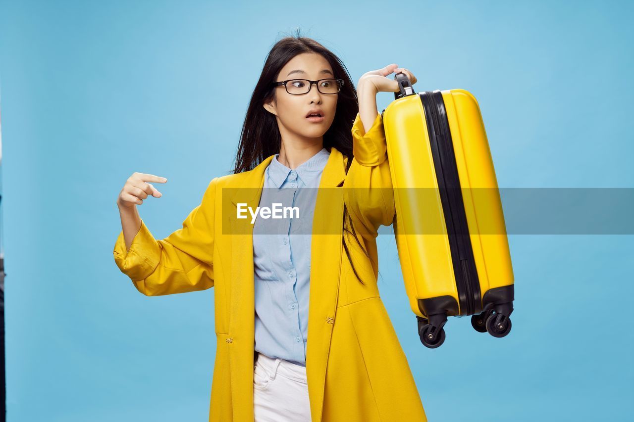 BEAUTIFUL YOUNG WOMAN STANDING AGAINST YELLOW BLUE SKY