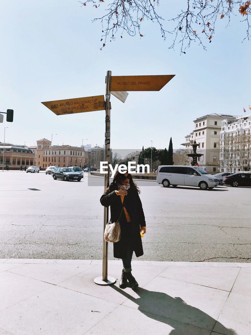 WOMAN STANDING ON STREET AGAINST SKY