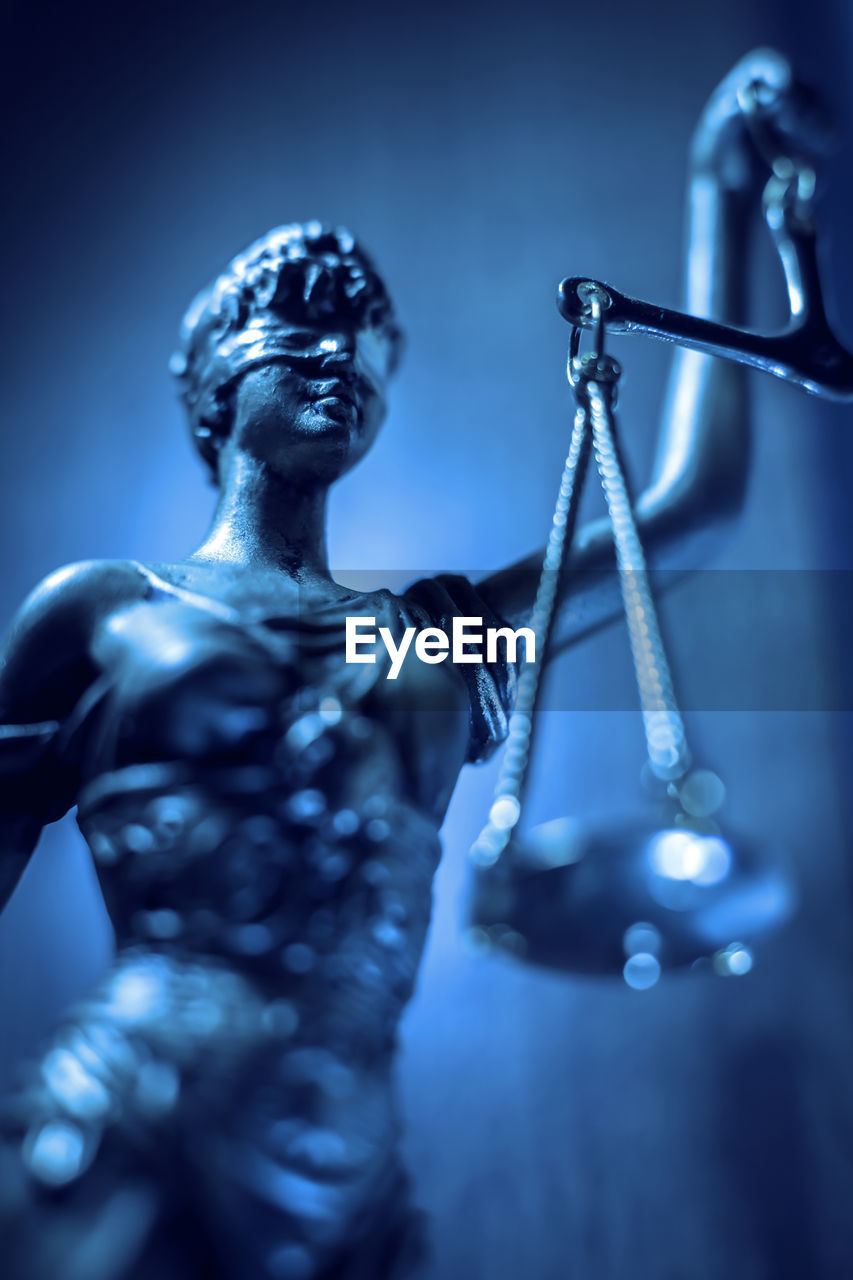 Lady justice statue with scales and blindfold on blue background