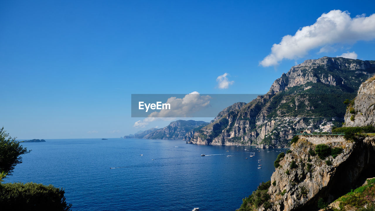 Scenic view of sea and mountains against blue sky