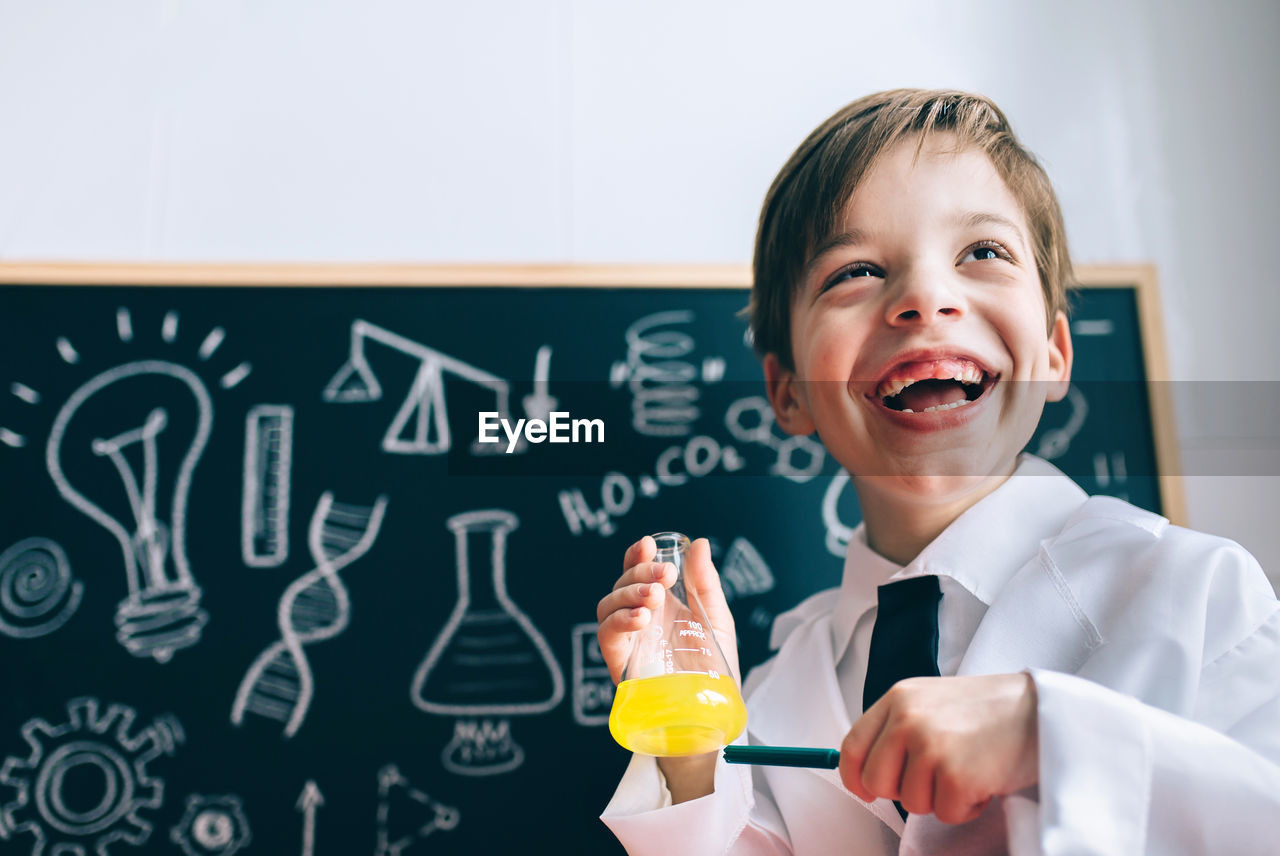 Boy wearing lap coat while standing in classroom