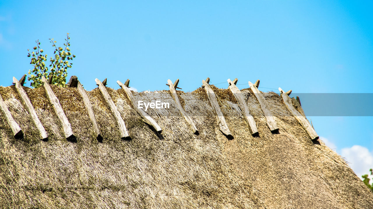 Low angle view of thatched roof against blue sky