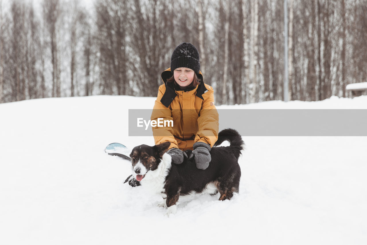 A girl plays with a corgi dog in a winter park