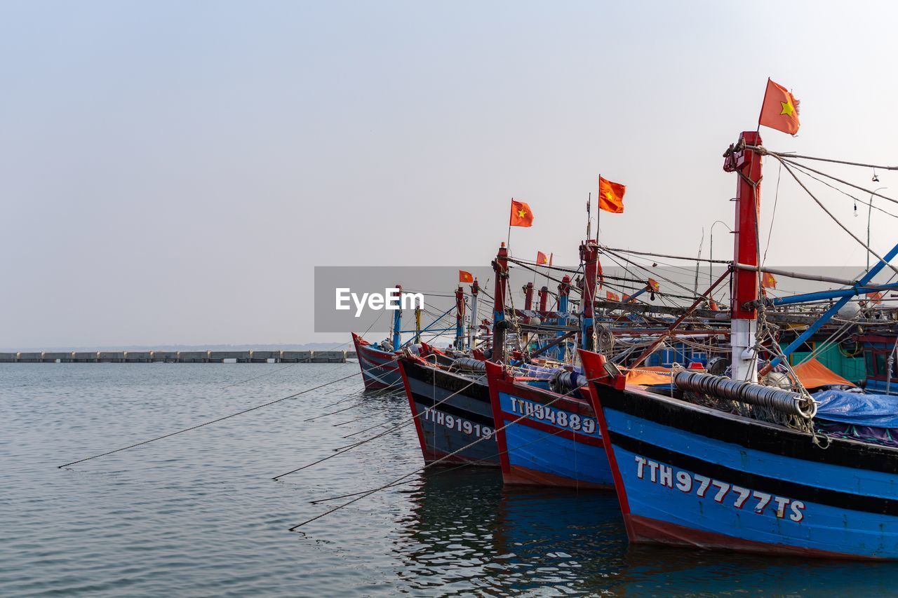 BOAT MOORED IN SEA AGAINST CLEAR SKY