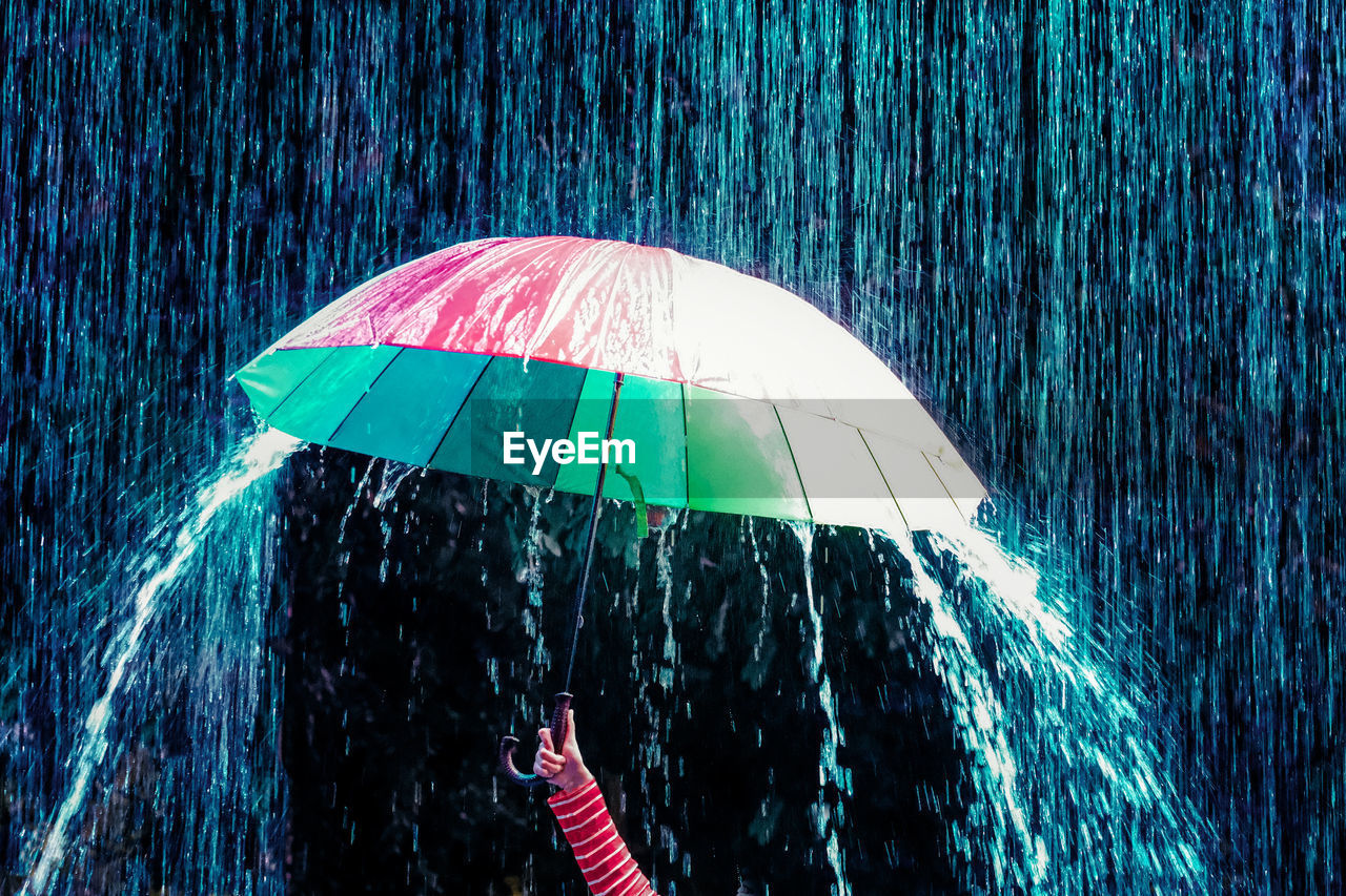 Cropped hand of woman holding umbrella during monsoon