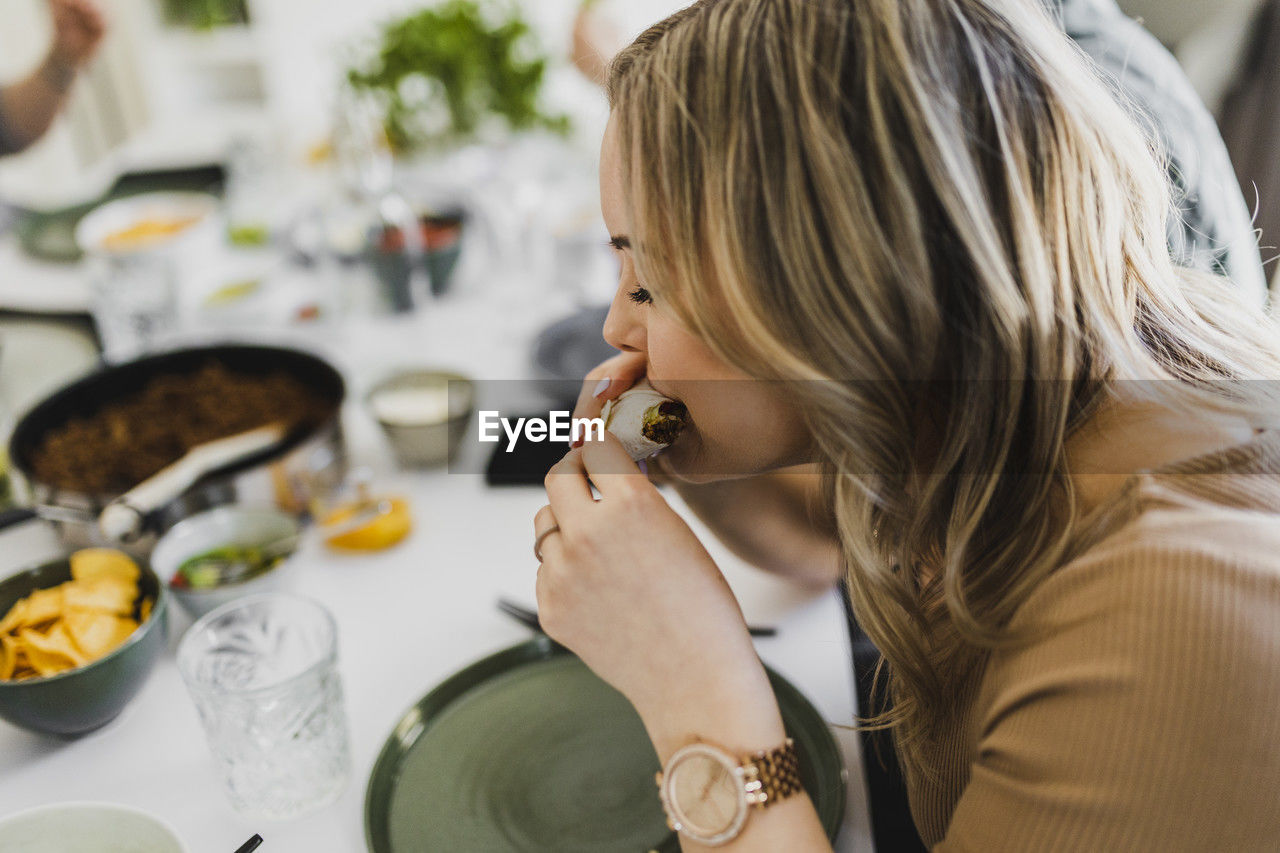 Woman eating mexican burrito at home