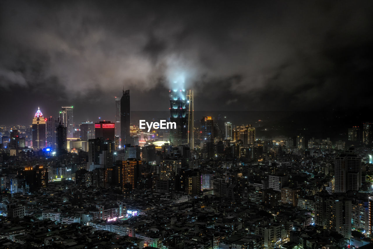 Panoramic view over taipei 101 and surrounding buildings at night during a rain storm. 