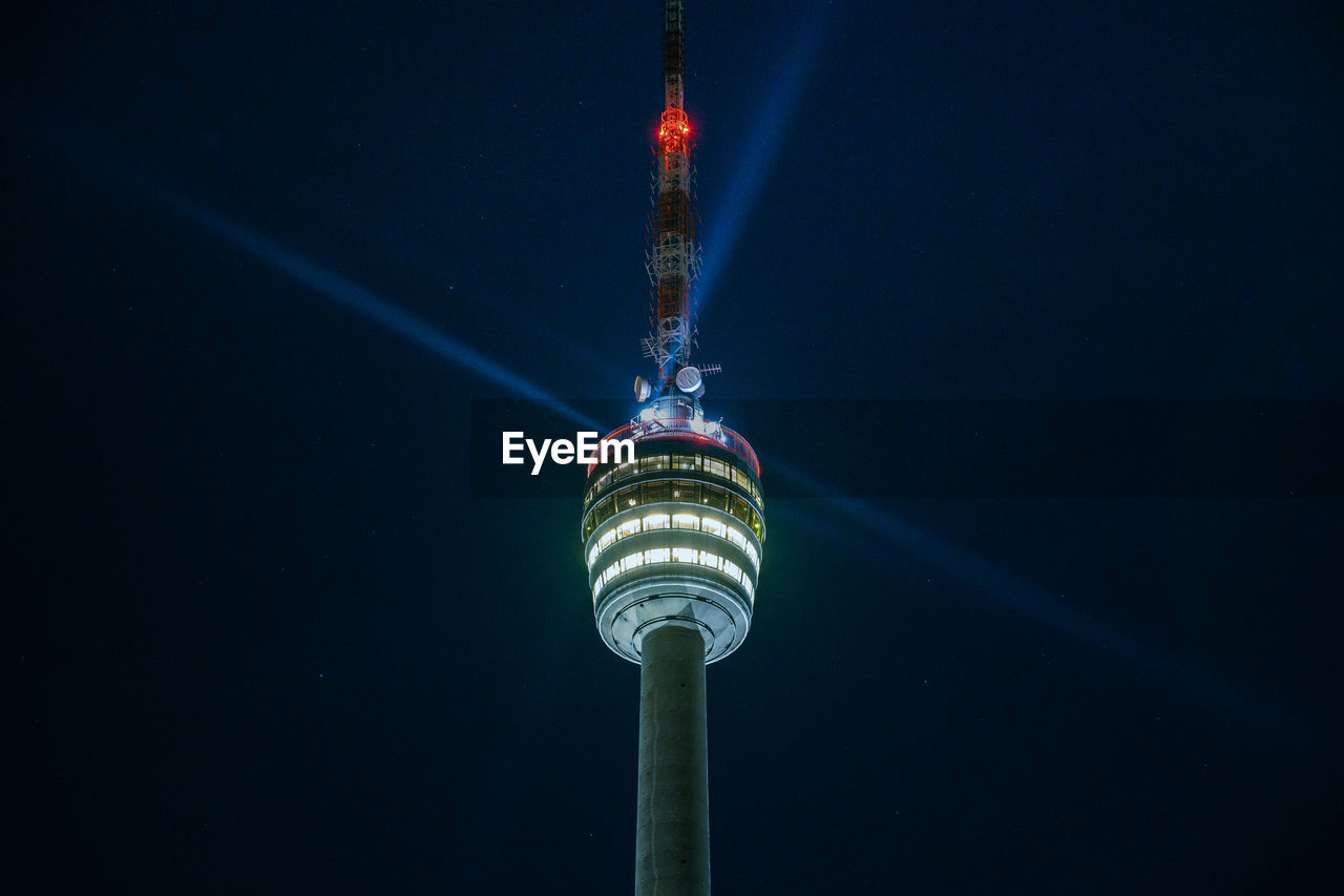 Stuttgart television tower against night sky with stars and light beams, germany