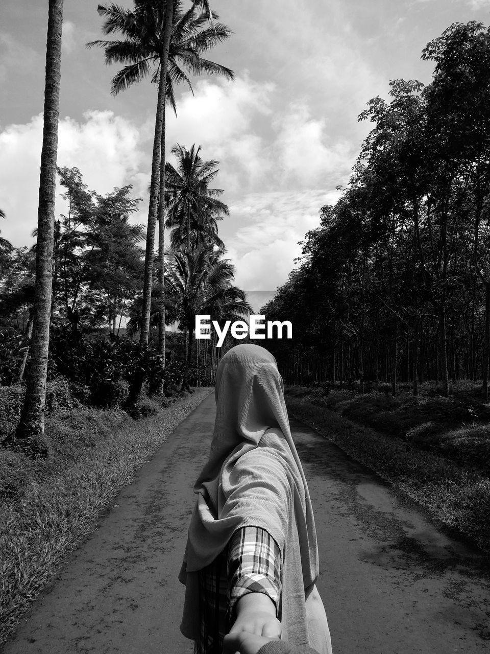 REAR VIEW OF MAN WALKING ON ROAD AMIDST TREES