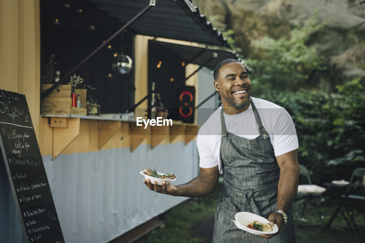 Smiling male seller with food looking away in park