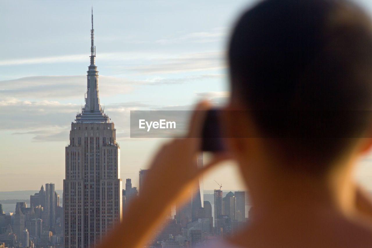 Rear view of man photographing new york cityscape and empire state