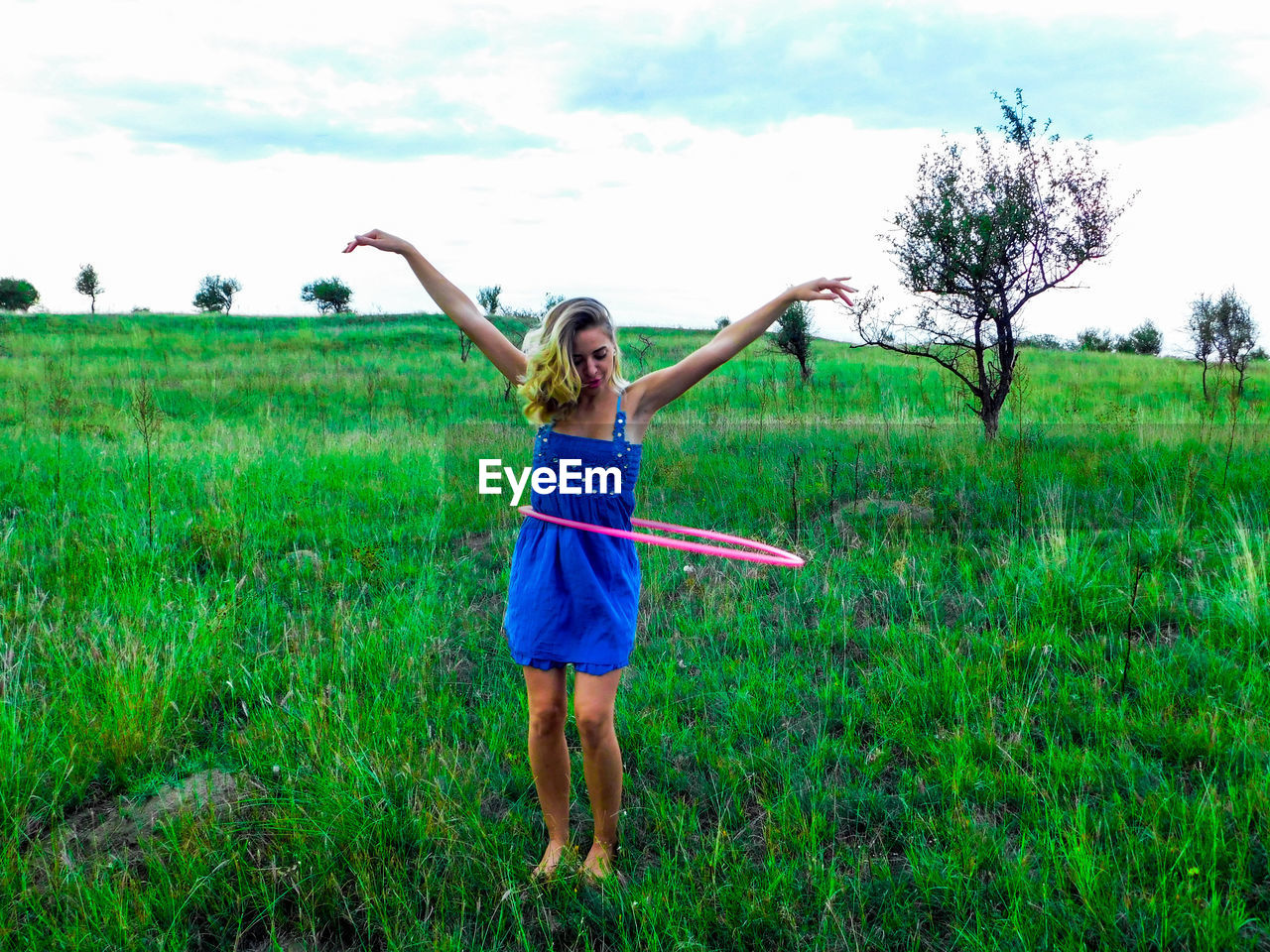 FULL LENGTH OF HAPPY WOMAN STANDING ON FIELD