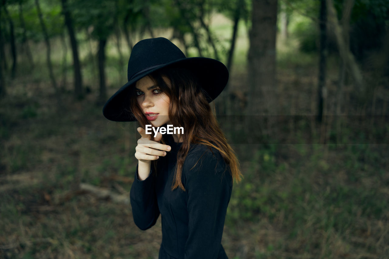 portrait of young woman wearing hat standing in forest