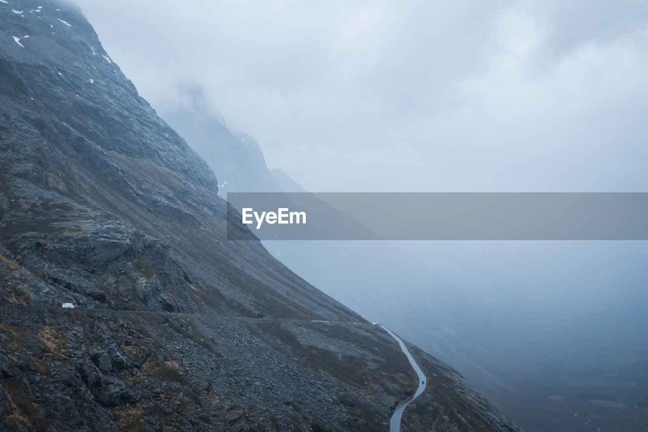 Rocky mountainside with road and mist. distant. panoramic.