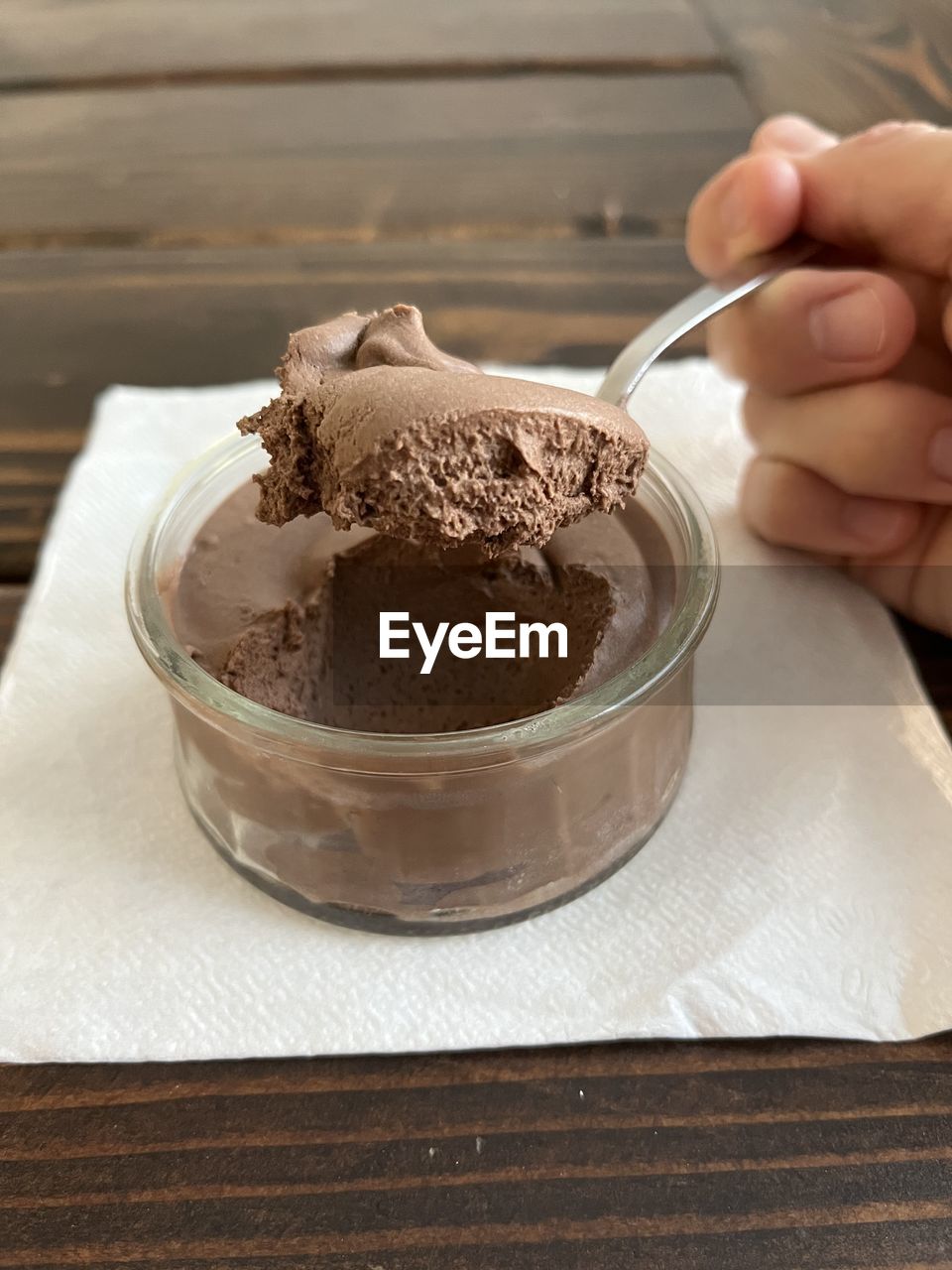 hand, food and drink, one person, ice cream, food, chocolate ice cream, holding, chocolate, wood, indoors, dessert, baked, sweet food, adult, sweet, icing, women, dairy, freshness, lifestyles, close-up, table, eating utensil, kitchen utensil, household equipment