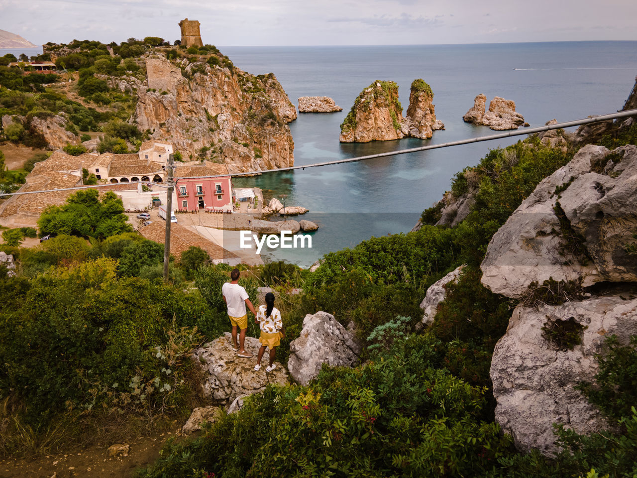 PEOPLE LOOKING AT VIEW OF SEA AND ROCKS