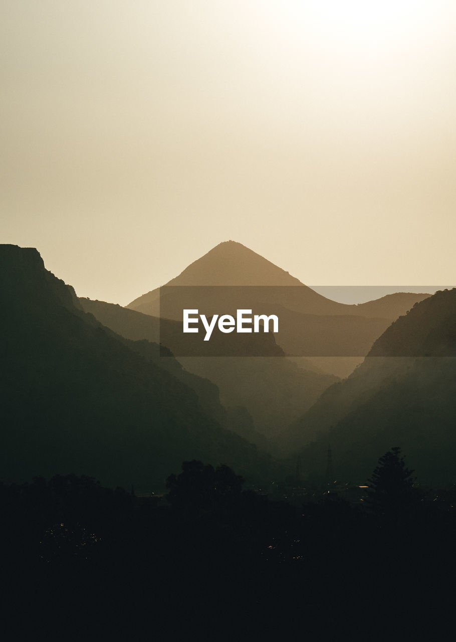 scenic view of mountains against clear sky during sunset