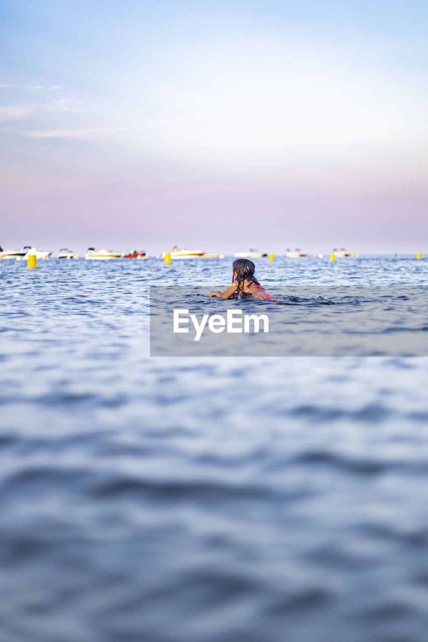 People swimming in sea against sky