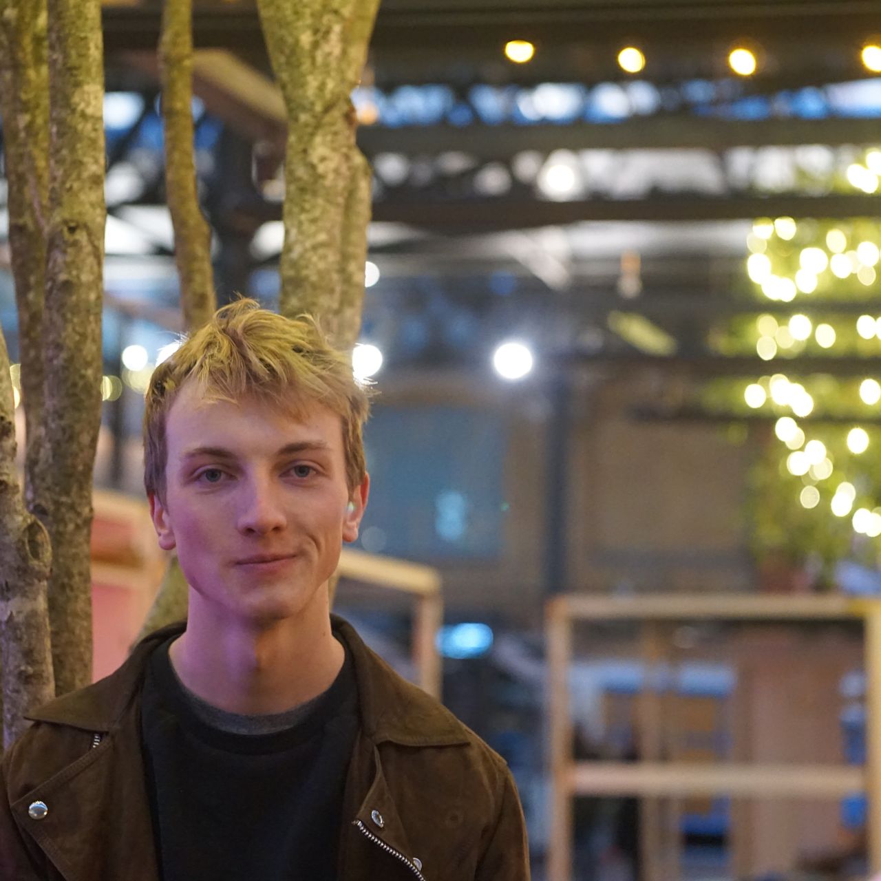 Portrait of young man standing against illuminated lights