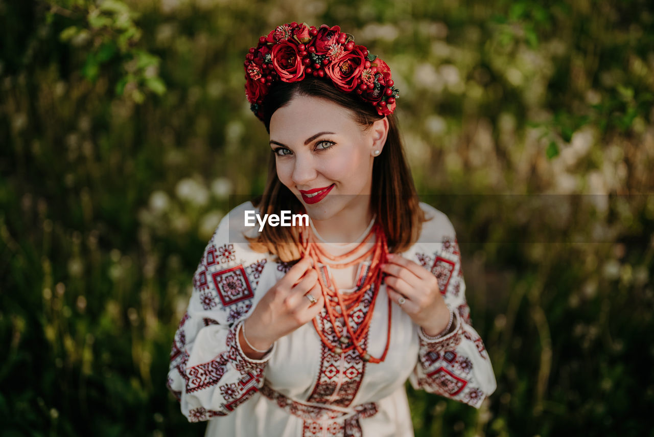 portrait of young woman looking away while standing against plants