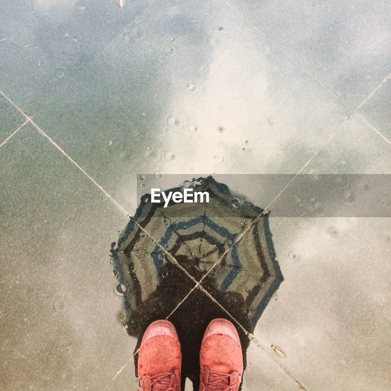 Low section of person standing in front of puddle