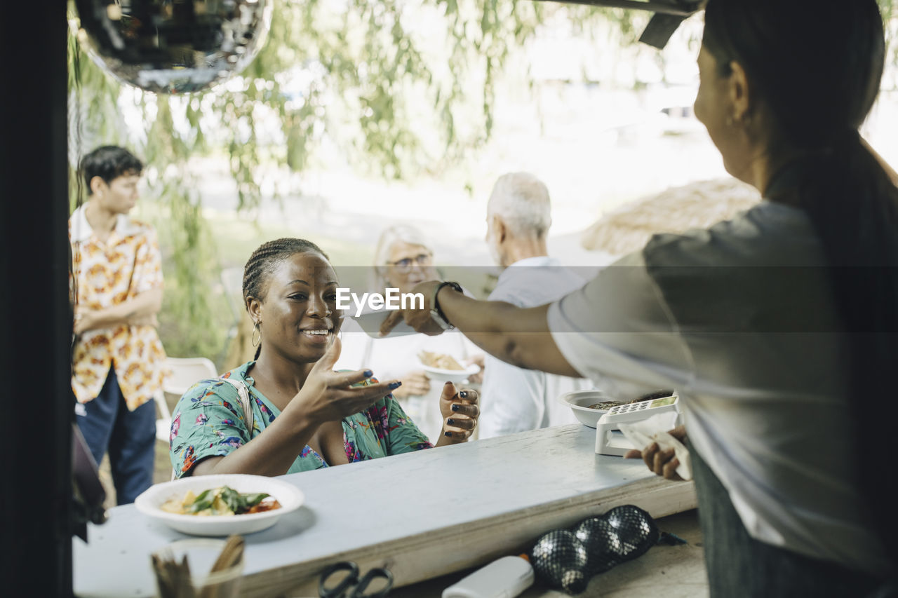 Female seller serving food to customer in park