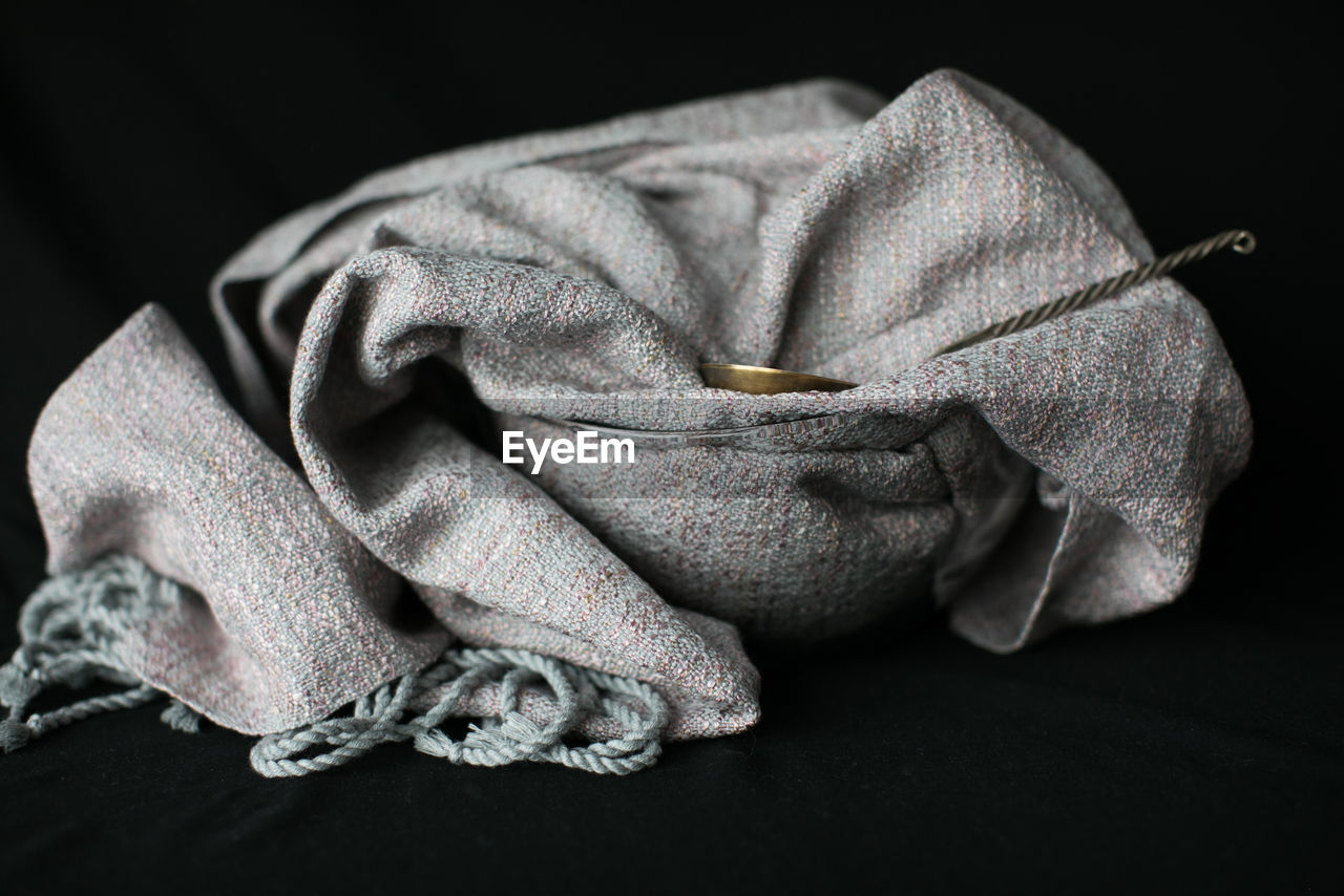 Close-up of fabric and ladle in bowl against black background