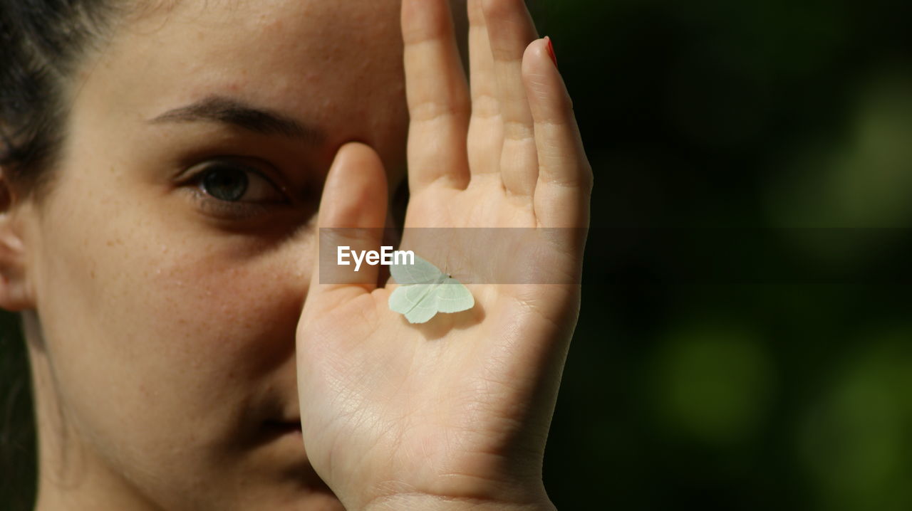 CLOSE-UP PORTRAIT OF HUMAN HAND HOLDING LEAF