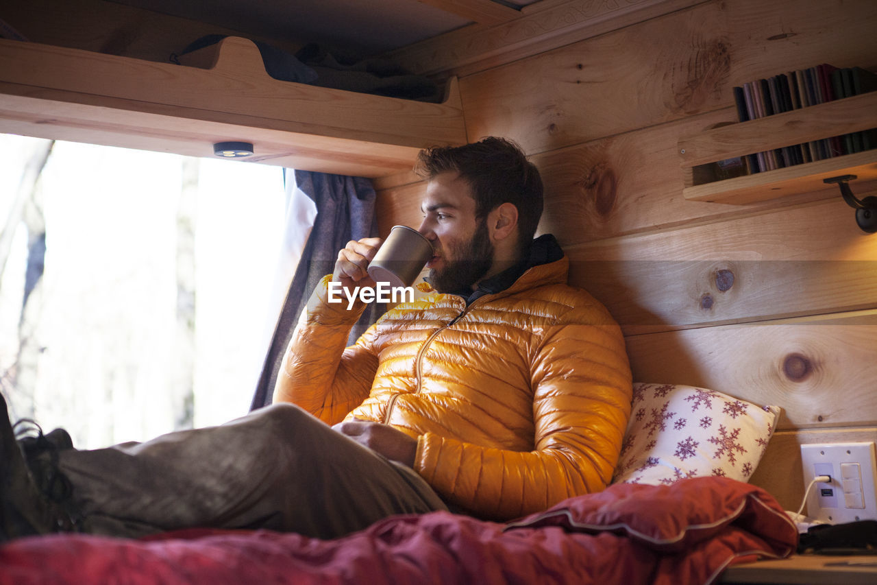 Man having drink while sitting in camper van