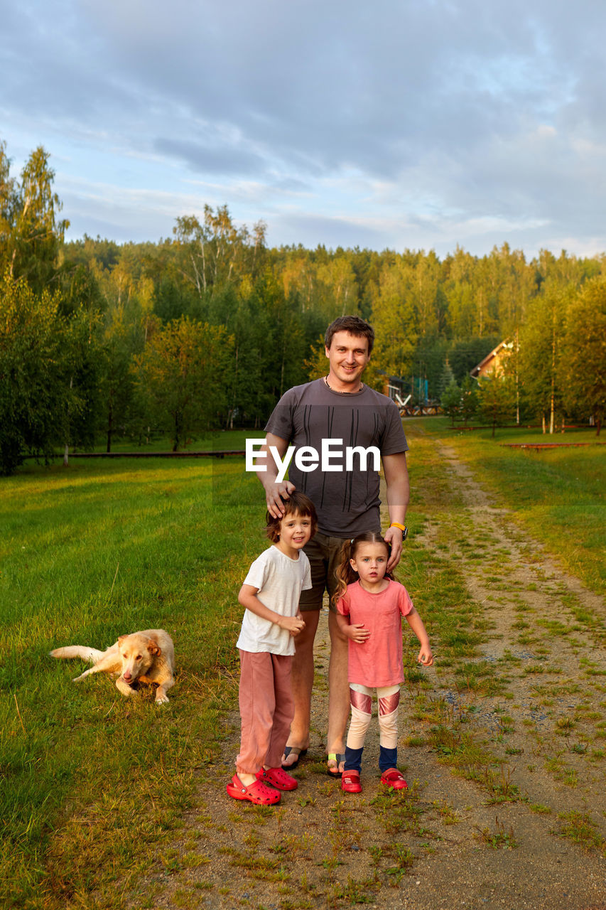 Father with kids and dog on countryside road