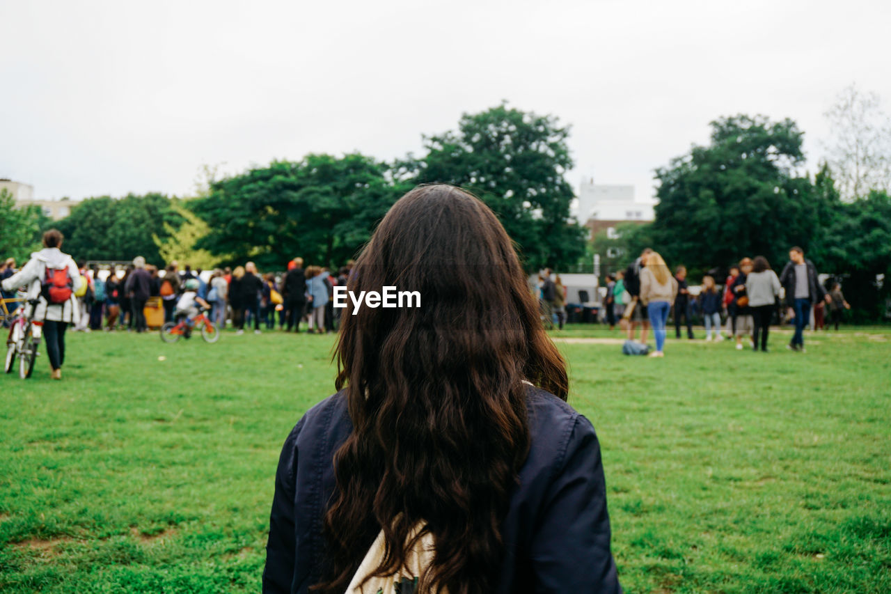 Rear view of woman standing on grassy field at park