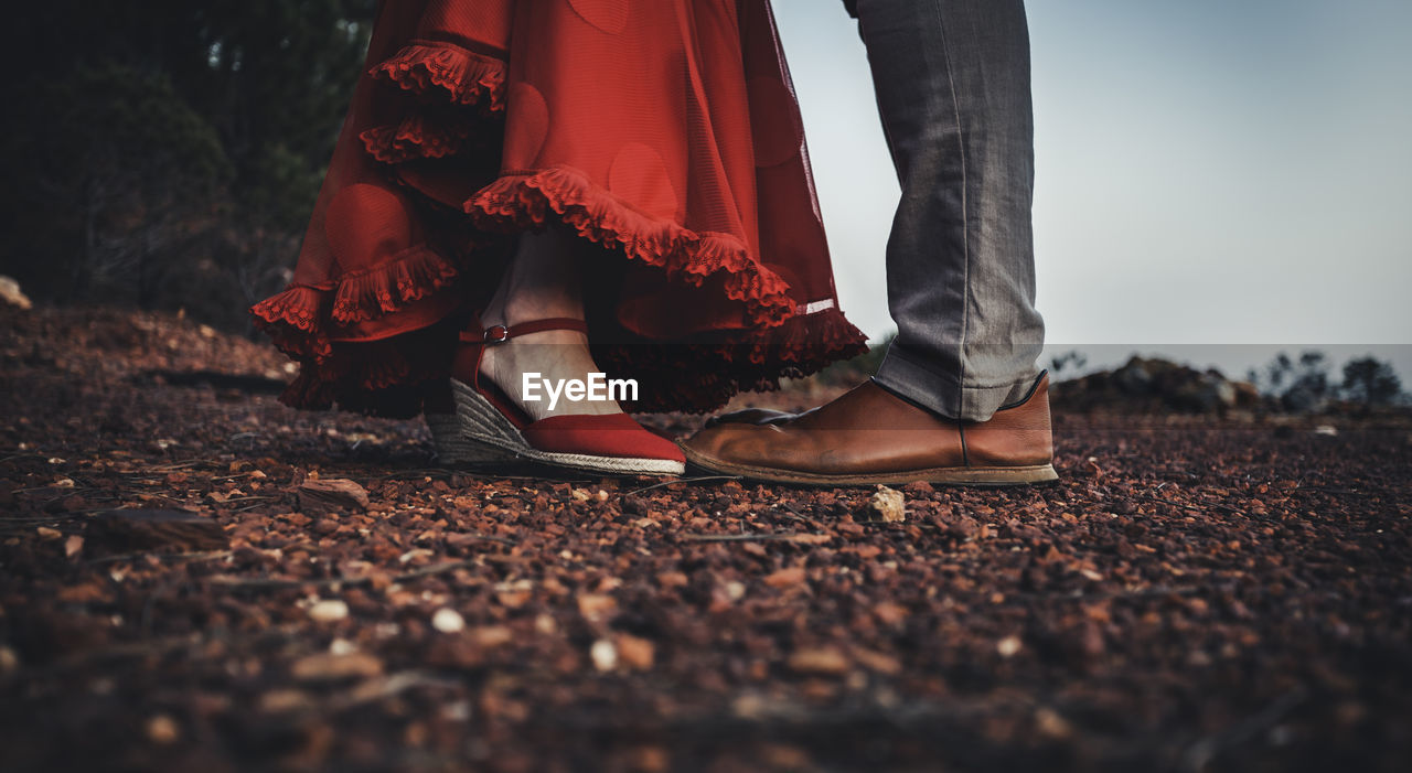 Low section of couple standing on pebbles