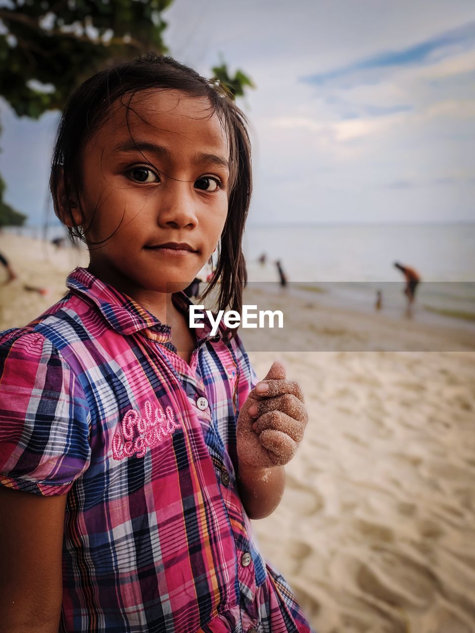 Portrait of cute girl standing at sandy beach 