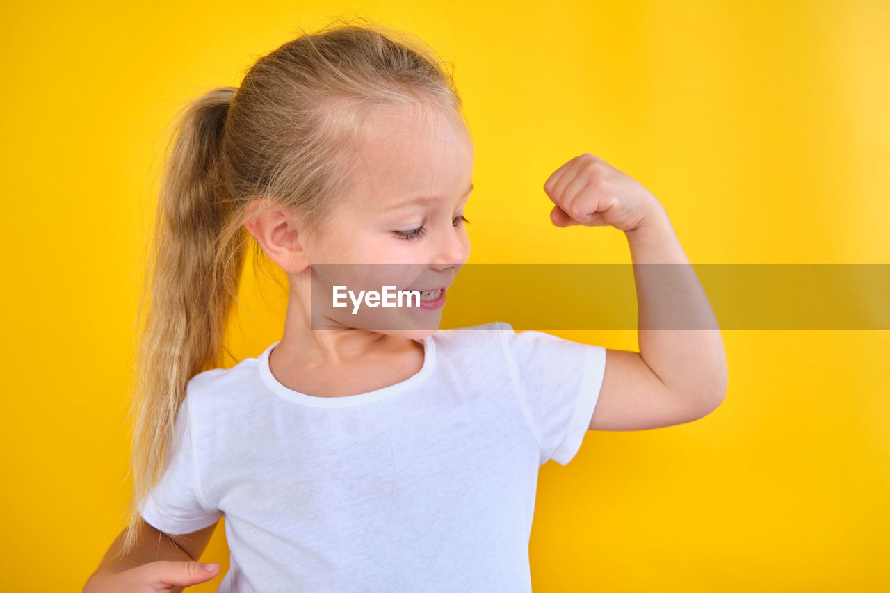Portrait strong preschool little girl showing flexing arm muscle smile isolated