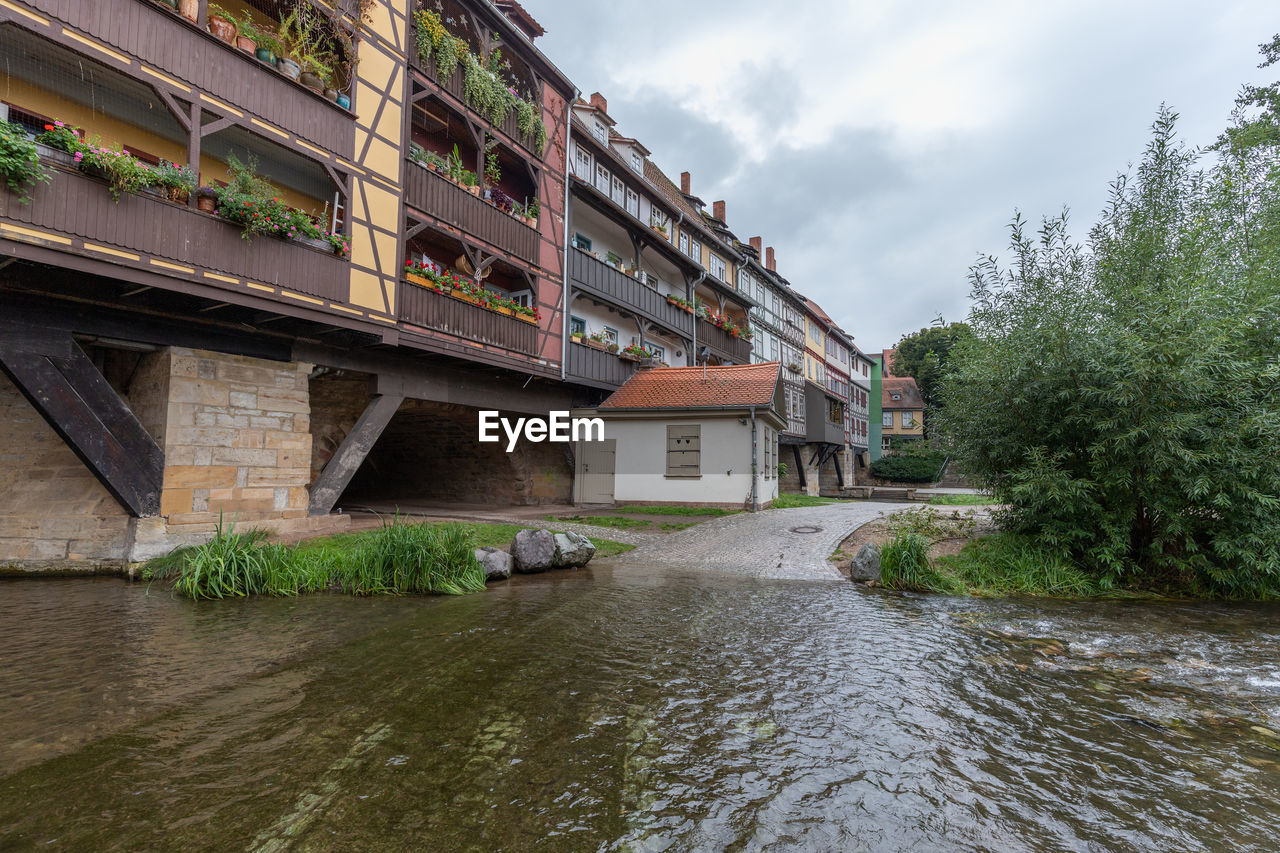 BRIDGE OVER RIVER BY BUILDINGS AGAINST SKY