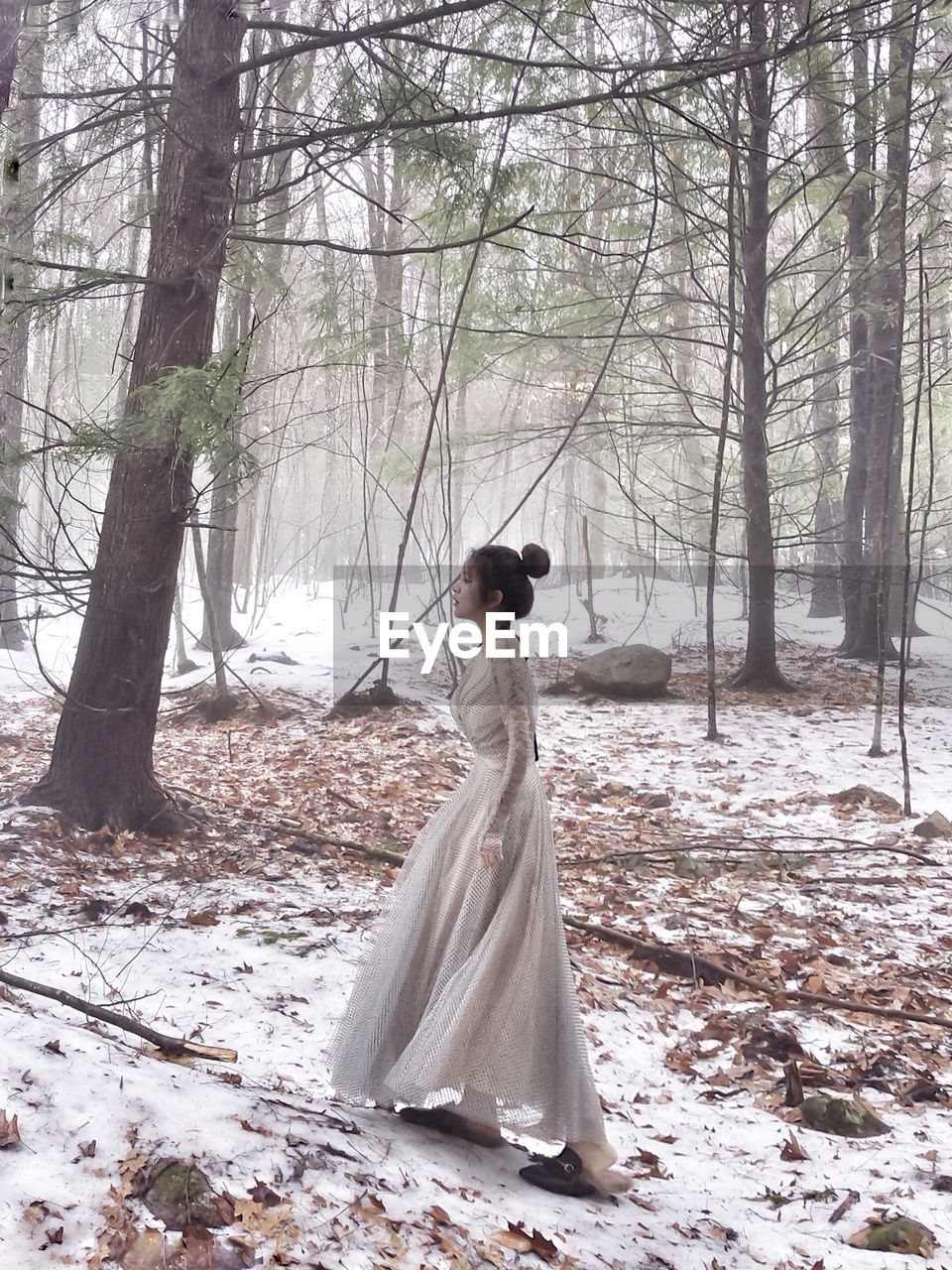 Side view of woman walking in forest during winter