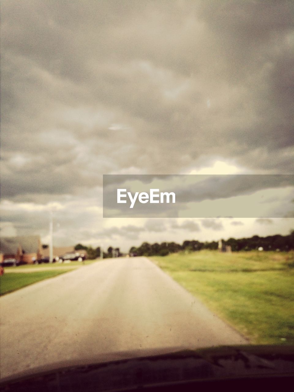 ROAD PASSING THROUGH FIELD AGAINST CLOUDY SKY