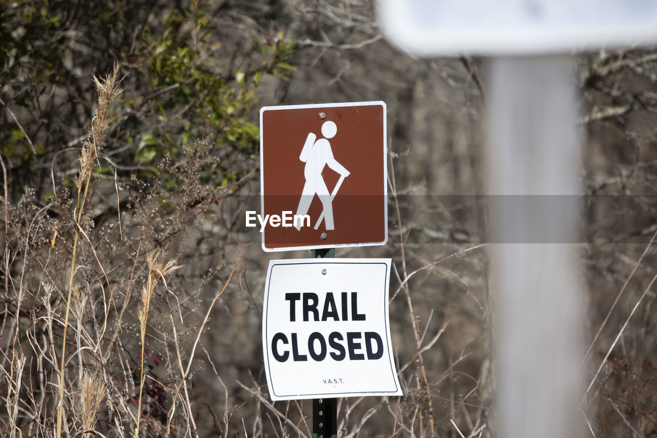 sign, communication, guidance, warning sign, road sign, no people, information sign, nature, road, representation, symbol, plant, text, day, human representation, outdoors, western script, traffic sign, arrow symbol, directional sign, street sign, land