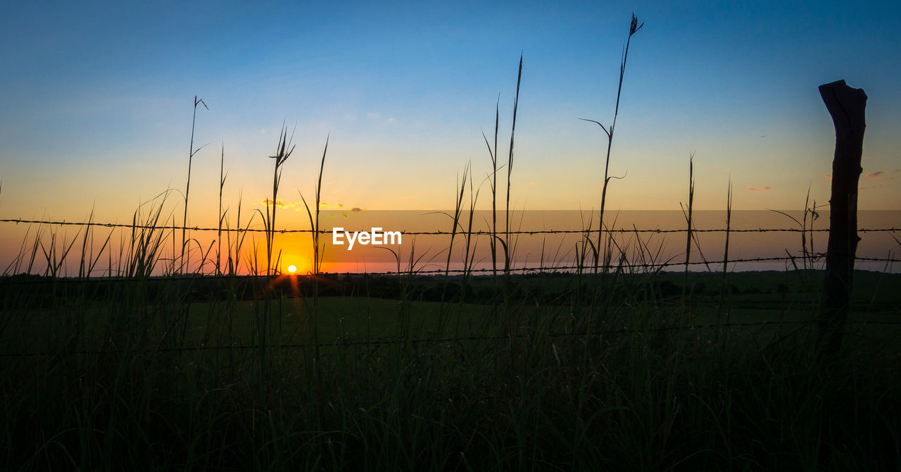 Scenic view of silhouette field against sky during sunset