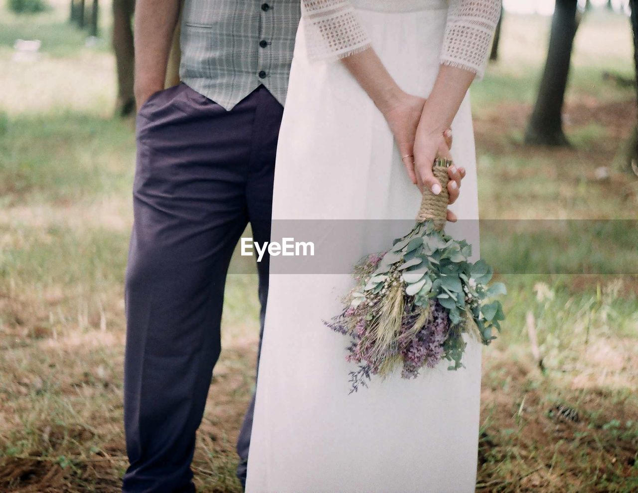 Midsection of couple standing on grassy field