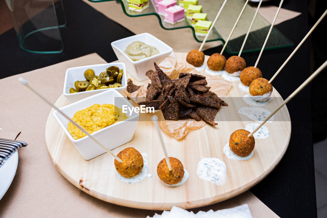 Plate with appetizers, catering service. falafel balls on cream sauce. sautéed spreads and rye bread