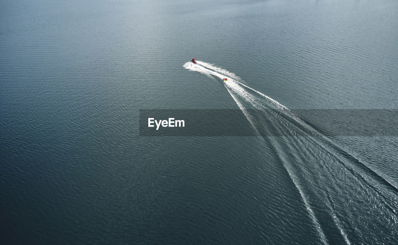 Sportsperson water skiing on lake behind motorboat