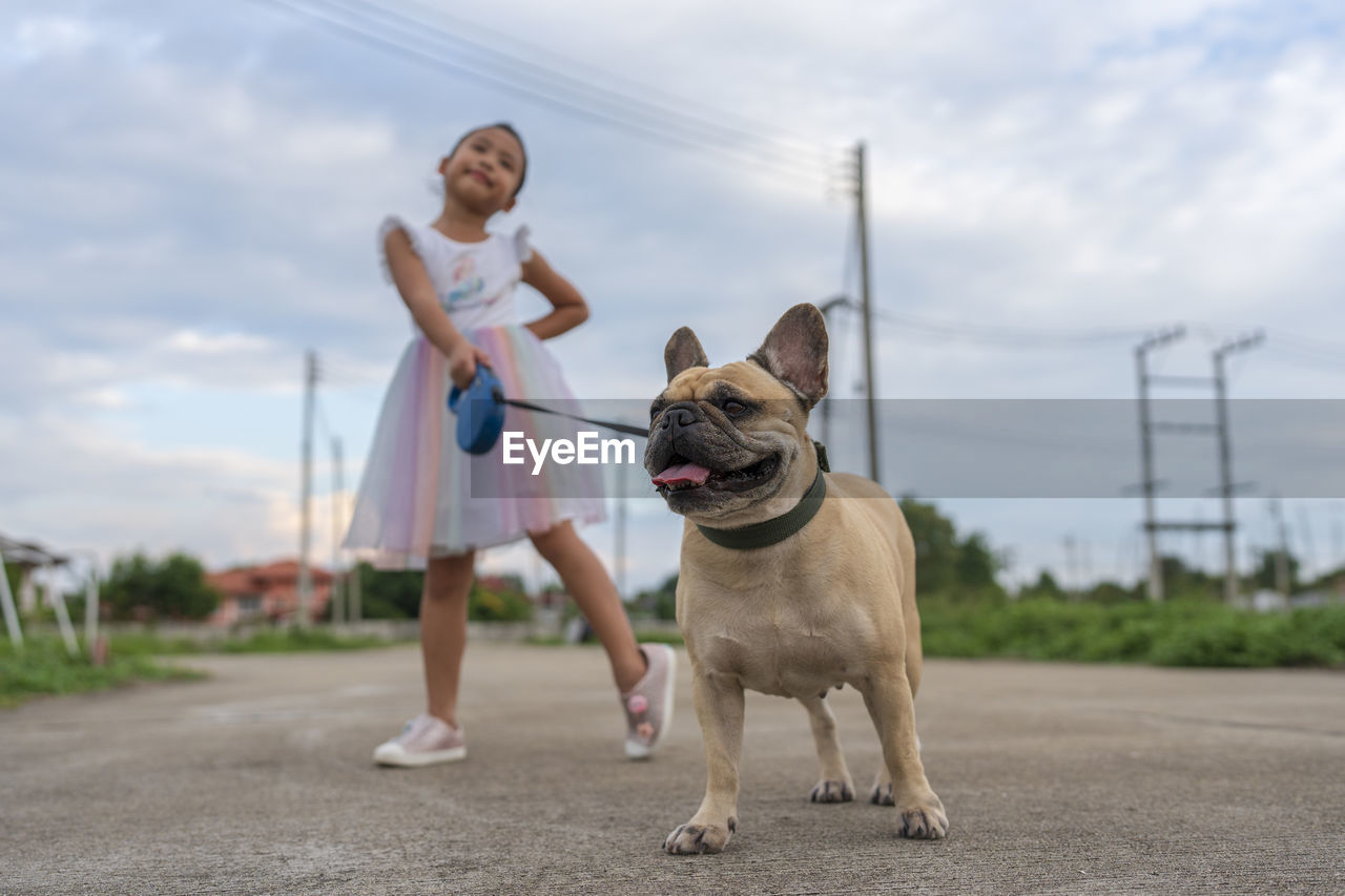 portrait of young man with dog standing on road