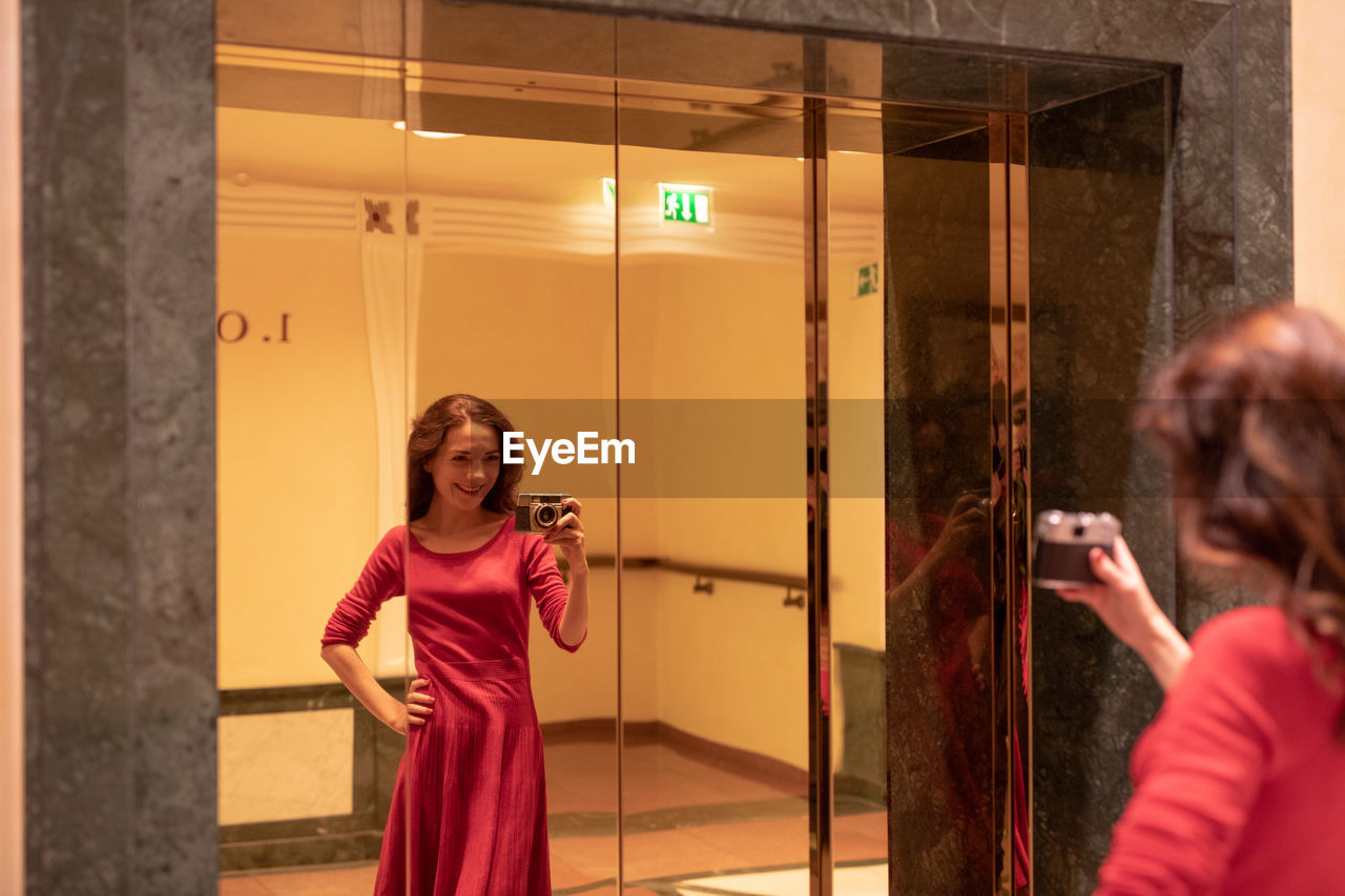 Happy woman taking photograph in mirror